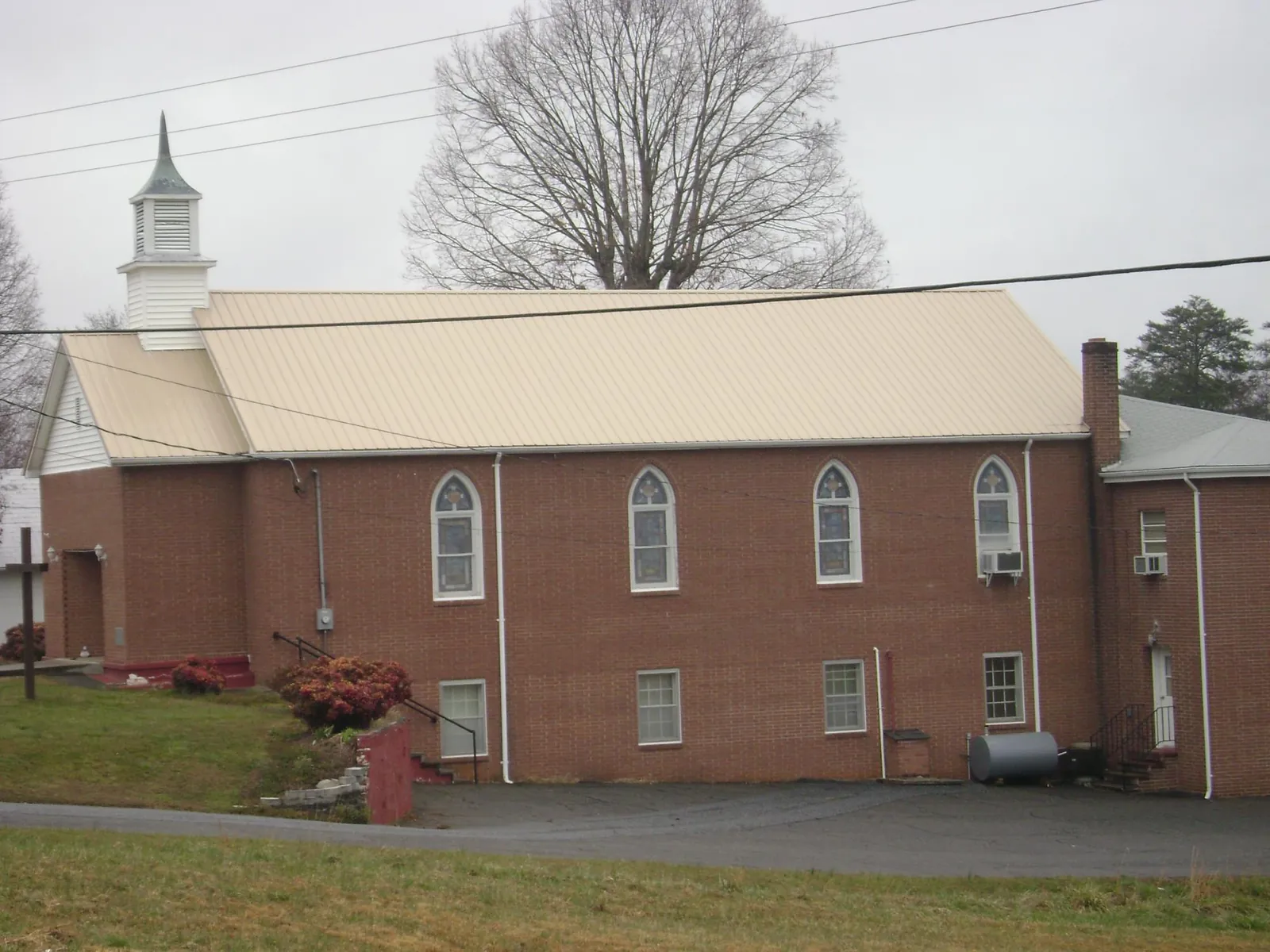 New tan metal roof on a brick church with a white steeple in Pembroke Pines