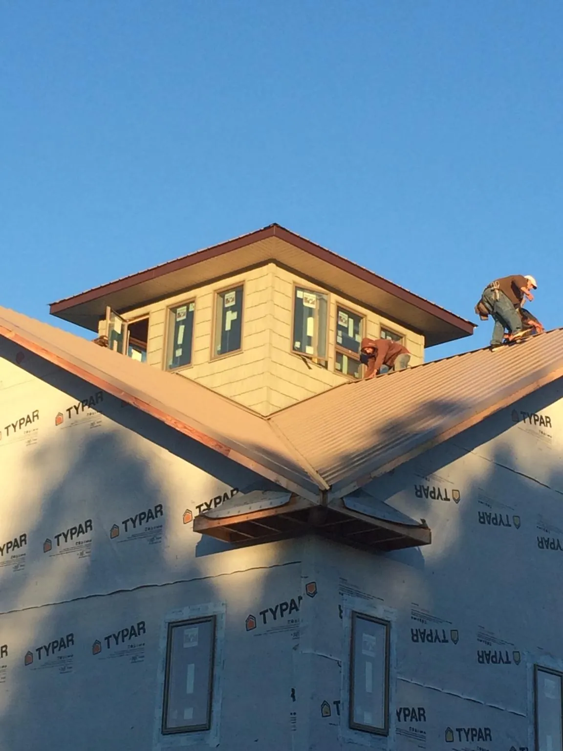 Roofers working around a rooftop cupola on a new metal roof at sunset — Roof Waterproofing in Pembroke Pines by Roofing Brothers